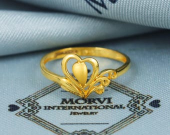 May include: A gold ring with a heart-shaped design. The ring is on a blue background with the text "Morvi International Jewelry".