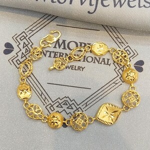 May include: A gold bracelet with a variety of intricate designs. The bracelet features a clasp and is made of multiple connected links.