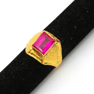May include: A gold ring with a large, rectangular, pink gemstone.