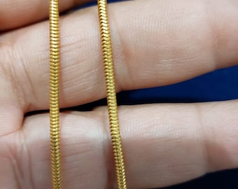 May include: A gold snake chain necklace. The chain is made of small, interlocking links that create a smooth, flowing look.