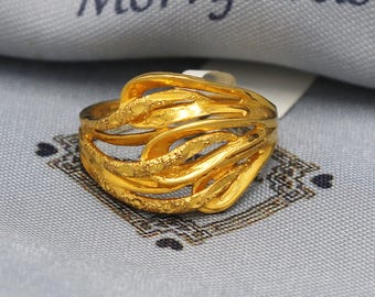 May include: A gold ring with a unique, abstract design. The ring is made of multiple interwoven bands that create a flowing, organic shape.