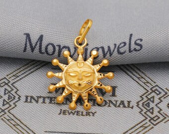 May include: A gold-colored sun pendant with a detailed face and radiating rays. The pendant is suspended from a small loop, ready to be added to a necklace. The background is a gray fabric with the word "Jewelry" visible.