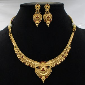 May include: A gold necklace and earrings set with a floral design and red, green, and white enamel accents.