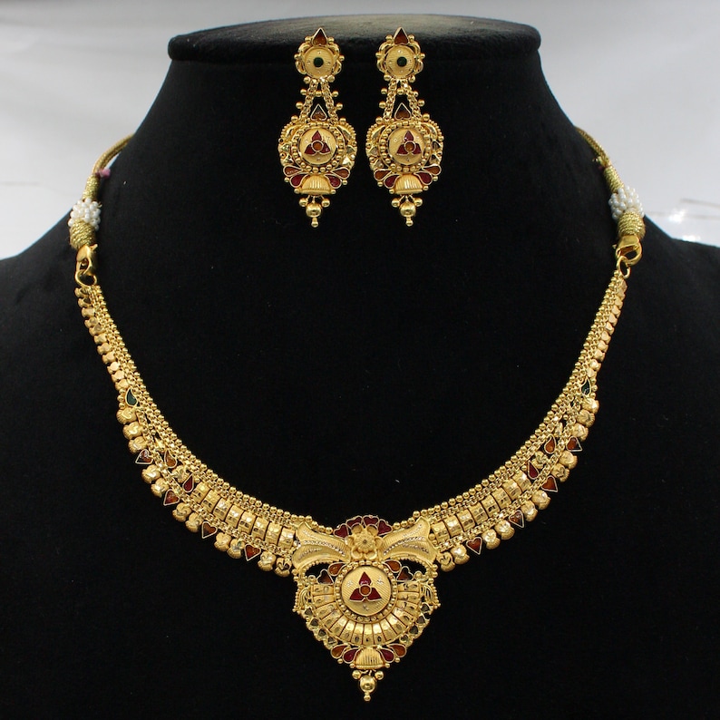 May include: A gold necklace and earrings set with a floral design and red, green, and white enamel accents.