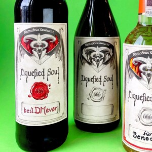 Puede incluir: Tres botellas de vino con etiquetas que dicen "Asmodeus' Favourite Liquefied Soul" y el número "666". Las botellas tienen tapas y etiquetas de diferentes colores. Una etiqueta dice "best DMever". El fondo es verde brillante.