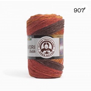Puede incluir: Un ovillo de hilo "AVORI Batik" en tonos marr&oacute;n, naranja y rojo. La etiqueta presenta el texto "MADAME TRICOTE PARIS" y "&Ouml;REN BAYAN". El n&uacute;mero "907" es visible en la esquina superior derecha. El hilo est&aacute; bien enrollado.