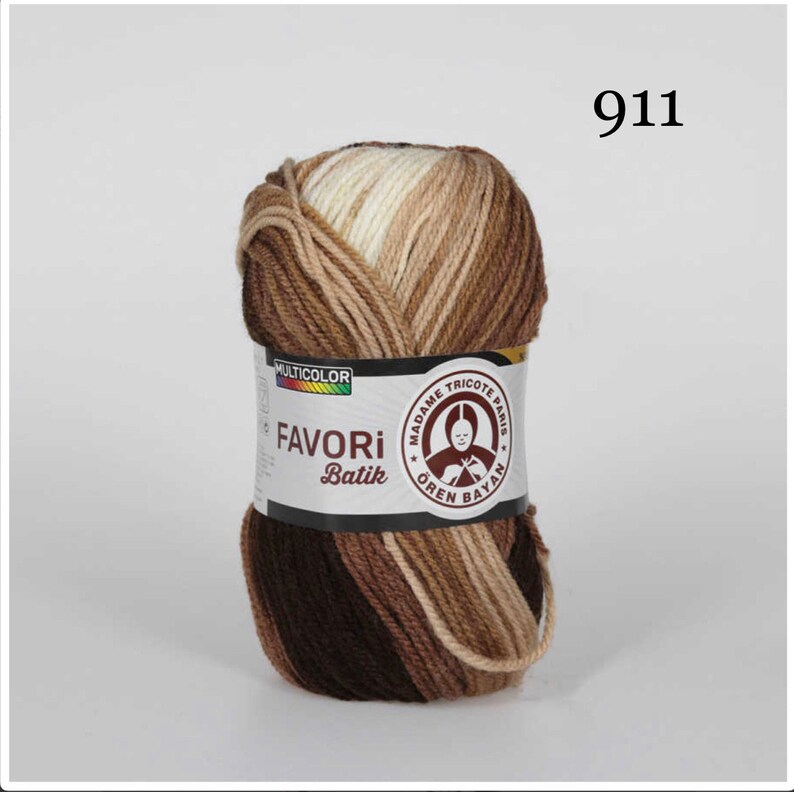 Puede incluir: Ovillo de lana multicolor con tonos marrones, beige y crema. La etiqueta dice "FAVORI Batik" y "911". La lana es de "MADAME TRICOTE PARIS".