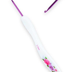 May include: A white crochet hook with a purple tip and a floral design. The hook is 2.5 mm.