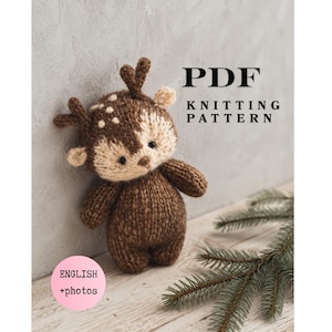 May include: A PDF knitting pattern featuring a small, hand-knitted brown deer toy with cream-coloured facial details and antlers. The text on the image reads PDF KNITTING PATTERN and ENGLISH +photos. The deer has a round body and small ears.