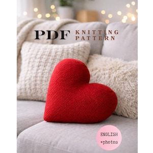 Könnte beinhalten: Ein PDF-Strickmuster-Dokument mit einem leuchtend roten herzförmigen Kissen. Der Text auf dem Dokument lautet PDF KNITTING PATTERN und ENGLISH +photos. Das Herzkissen hat eine sichtbare Strickstruktur und liegt auf einem hellgrauen Sofa.