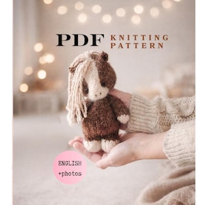 Puede incluir: Portada de un patrón de tejido PDF con un caballo tejido marrón y blanco, con crin beige. El texto "PDF Knitting Pattern" está en la parte superior y "English + photos" en la inferior.
