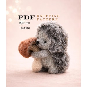 Puede incluir: Un patrón de tejido PDF en inglés con fotos que muestra un erizo tejido sosteniendo un hongo marrón. El erizo tiene una espalda gris difusa y un cuerpo gris claro liso. El texto dice PDF KNITTING PATTERN ENGLISH +photos.