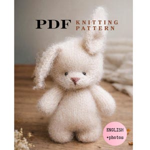 May include: A PDF knitting pattern featuring a fuzzy, cream-colored stuffed rabbit with one upright ear and one floppy ear. The text reads PDF KNITTING PATTERN and ENGLISH +photos. The rabbit has dark eyes and a small, stitched pink nose.