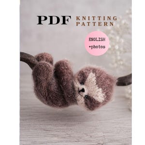 Könnte beinhalten: Titelbild für eine PDF-Strickanleitung mit einem braunen Faultier, das an einem Ast hängt. Das Faultier hat ein hellbraunes Gesicht und dunkle Augen. Der Text "PDF KNITTING PATTERN" steht oben, mit "ENGLISH + photos" in einem rosa Kreis.
