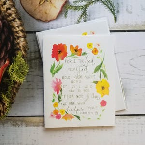May include: Greeting cards with floral watercolor design. The cards feature a wreath of orange, yellow, and pink flowers surrounding the text "For I, the Lord your God...Fear not, I am the one who helps you." from Isaiah 41:13.