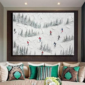 Könnte beinhalten: Abstraktes Gemälde von Skifahrern auf einer schneebedeckten Piste. Das Kunstwerk zeigt Skifahrer in Rot und Schwarz vor einem strukturierten weißen Hintergrund mit immergrünen Bäumen. Das Gemälde ist in einem dunkelbraunen Rahmen gerahmt und hängt über einem beigen Sofa mit dekorativen Kissen.