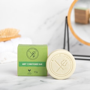 May include: A green box with the text "Battle Green" and a trident logo. The box says "Mint Conditioner Bar" and "55g". A white round bar of soap with the same logo is next to the box.