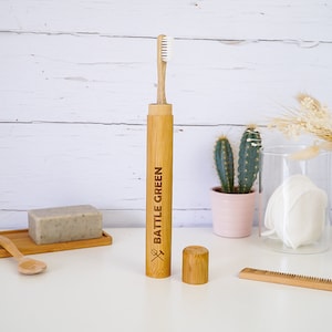 Puede incluir: Un cepillo de dientes de bamb&uacute; y un estuche con las palabras "BATTLE GREEN" grabadas en el estuche. El estuche tiene una peque&ntilde;a tapa.