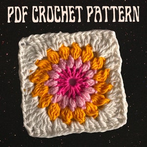 May include: A crochet square with a pink and yellow flower design. The square is white with a border of white crochet stitches. The flower is made of pink and yellow yarn and has a center of pink yarn. The image includes the text "PDF CROCHET PATTERN".