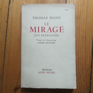 May include: A white book cover with the title "Le Mirage" by Thomas Mann. The book is in French and is a translation of the German novel "Die Betrogene". The cover also includes the name of the translator, Louise Servicen, and the publisher, Editions Albin Michel.