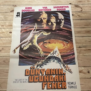 May include: A vintage movie poster for the film "The Light at the Edge of the World" starring Kirk Douglas, Yul Brynner, and Samantha Eggar. The poster features a dramatic image of a man falling towards a swirling black hole in space. The title of the film is written in large, bold letters in Turkish.