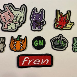 May include: A set of ten embroidered iron-on patches featuring various cartoon characters, including a pumpkin, a crown, a gummy bear, and a monster with multiple eyes. The patches are in various colors, including green, red, orange, and purple.