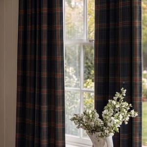 Puede incluir: Cortinas de cuerpo entero con un patrón de cuadros en verde oscuro, azul marino y naranja óxido. La tela cuelga de una barra de metal oscuro con remates dorados. Las cortinas están plisadas en la parte superior y enmarcan una ventana.
