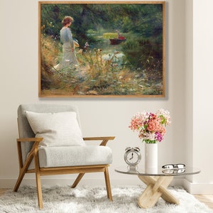 Peut inclure: Une peinture repr&eacute;sentant une femme en robe blanche debout au bord d'une rivi&egrave;re, regardant un bateau avec deux personnes &agrave; bord. La rivi&egrave;re est bord&eacute;e d'arbres et de buissons verts.