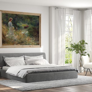Peut inclure: Un lit rembourr&eacute; gris avec une literie blanche et un tableau encadr&eacute; d'une femme debout dans une for&ecirc;t au bord d'un lac. Le tableau est dans un cadre en bois clair. Le lit est dans une chambre avec des rideaux blancs et un fauteuil blanc.