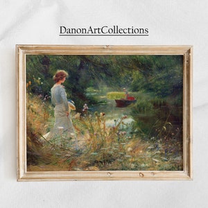 Peut inclure: Une peinture encadr&eacute;e repr&eacute;sentant une femme en robe blanche debout dans un champ de fleurs sauvages, regardant vers une rivi&egrave;re. Un homme dans un bateau rame sur la rivi&egrave;re en arri&egrave;re-plan. La peinture est dans un cadre en bois clair.