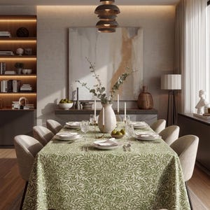 May include: A dining room table set for a meal, featuring a green leaf-patterned tablecloth. The table is set with white plates, glasses, and silverware. The room has a neutral color palette with a large abstract painting and a modern light fixture.