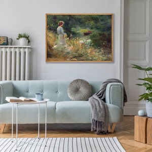 Peut inclure: Une peinture encadr&eacute;e repr&eacute;sentant une femme en robe blanche debout au bord d'une rivi&egrave;re. La rivi&egrave;re est entour&eacute;e d'arbres verts et il y a un petit bateau dans l'eau.