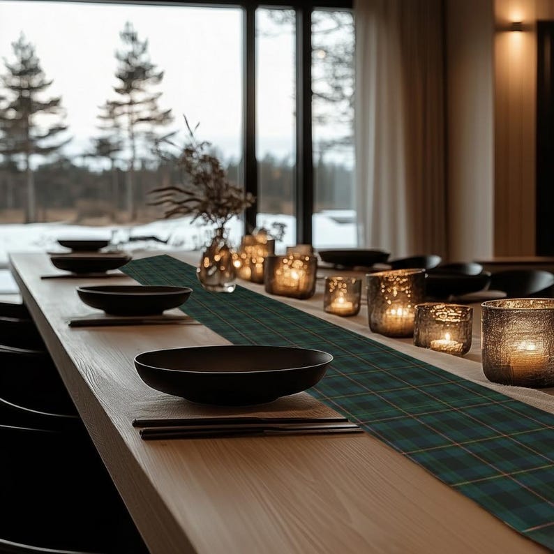May include: A dining table set for a meal, featuring black bowls, chopsticks, and a green plaid table runner. Lit candles in glass holders and a vase with dried flowers add ambiance. The table is set near a large window.