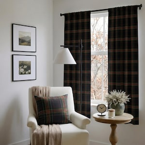 Puede incluir: Un par de cortinas largas con un patr&oacute;n de cuadros en verde oscuro, negro y naranja colgadas de una barra negra. Un sill&oacute;n blanco con un coj&iacute;n de cuadros a juego y una manta beige se sit&uacute;a frente a la ventana.