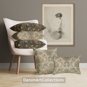 May include: Four decorative throw pillows with floral and geometric patterns in shades of blue, gold, and beige. The pillows are arranged on a white chair with wooden legs. A framed drawing of a woman is hanging on the wall behind the chair.