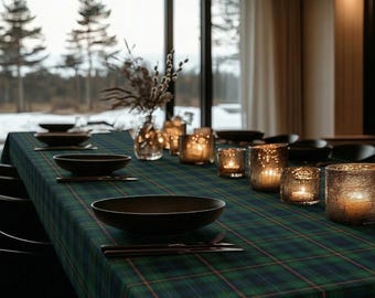 May include: A dining table set for a meal, featuring a green and blue plaid tablecloth. Black plates, silverware, and lit candle holders are arranged on the table. A vase of dried flowers sits in the center.