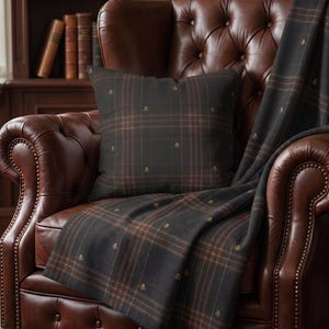 May include: A square throw pillow and a matching throw blanket featuring a dark charcoal gray fabric with a subtle brown plaid pattern and small, repeating embroidered thistle motifs throughout the textile design.