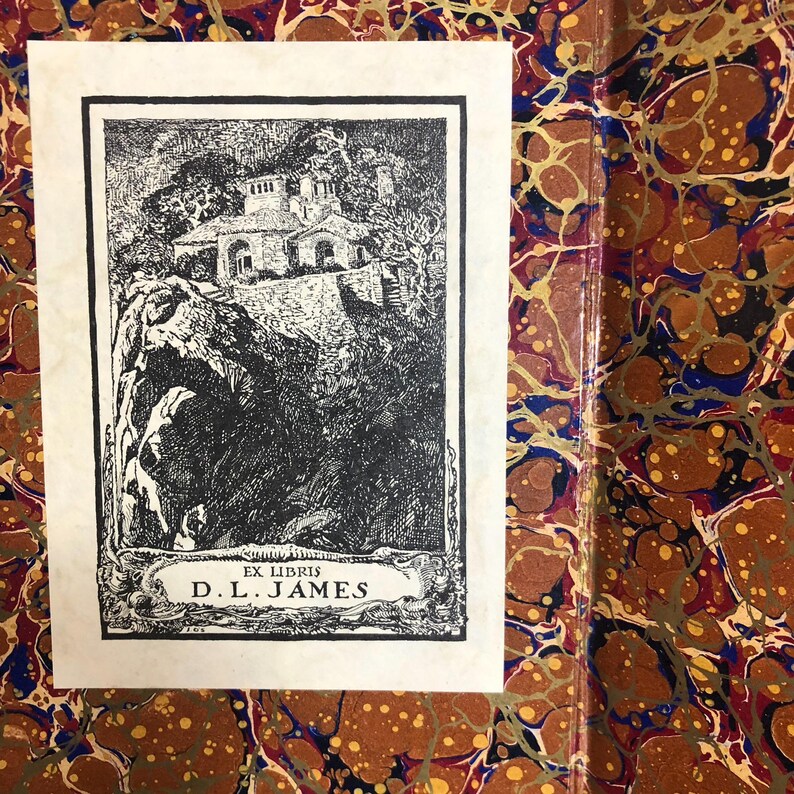 May include: A black and white bookplate featuring a detailed illustration of a building on a cliffside, with the text "EX LIBRIS D.L. JAMES" at the bottom. The bookplate is set against a marbled paper background.