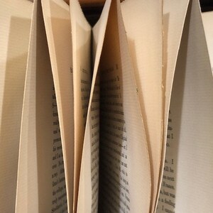Pu&ograve; includere: Primo piano di un libro con le pagine piegate. Le pagine sono ingiallite dal tempo e il testo &egrave; stampato in inchiostro nero.