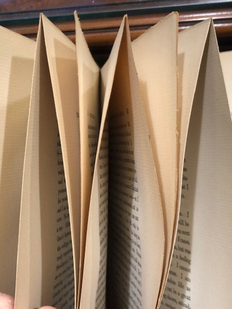 Pu&ograve; includere: Primo piano di un libro con le pagine piegate. Le pagine sono ingiallite dal tempo e il testo &egrave; stampato in inchiostro nero.