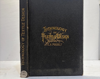 May include: A vintage book titled "Technology of Textile Design" by E.A. Posselt. The book has a black cover with gold lettering and a spine with vertical text. A coin rests at the base of the spine.
