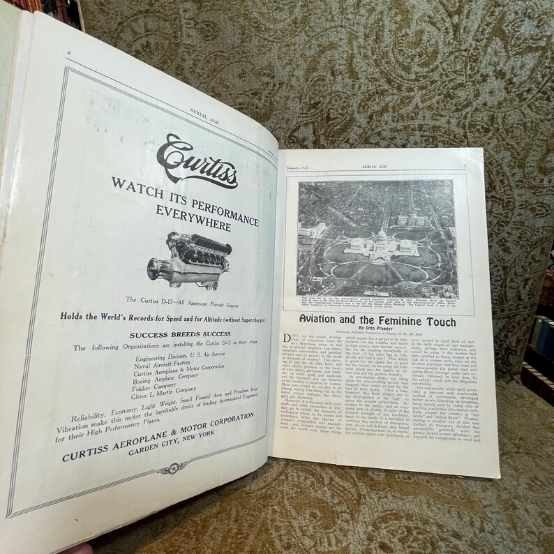 Puede incluir: Una p&aacute;gina de revista vintage con una foto en blanco y negro de un motor de avi&oacute;n Curtiss D-12. El texto en la p&aacute;gina dice "Curtiss, Watch Its Performance Everywhere" y "Holds the World's Records for Speed and for Altitude (without supercharger)".