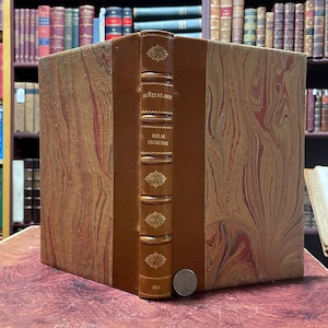 May include: A brown leather-bound book with gold accents and marbled paper covers. The title on the spine reads "Nunez de Arce" and "Obras Escogidas". The year "1913" is printed at the bottom of the spine.