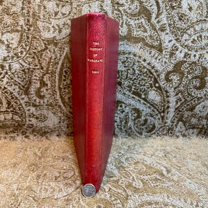 May include: A red leather-bound book with gold lettering on the spine. The title is "The History of Wargrave" by Reid.