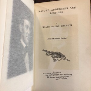 May include: Open book with the title "NATURE, ADDRESSES, AND LECTURES" by Ralph Waldo Emerson. The cover is off-white with black text and a small illustration of a plant. The book is a "New and Revised Edition" published in 1888.