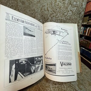 Puede incluir: Una p&aacute;gina de revista vintage con un art&iacute;culo sobre aeron&aacute;utica elemental y una ilustraci&oacute;n en blanco y negro de un biplano. La p&aacute;gina tambi&eacute;n presenta un anuncio de Valentine's Alspar, una empresa de barnices y pinturas, con un mapa que muestra una ruta de Wichita a Kansas City.