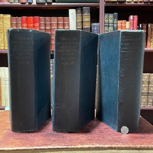 May include: Three dark blue hardcover books titled "Travels and Discoveries in North and Central Africa" by Heinrich Barth. The books are volumes I, II, and III.