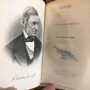 May include: An open book with a portrait of Ralph Waldo Emerson on the left page and the title "POEMS" on the right page. The book is an old edition, with the author's signature visible below the portrait.