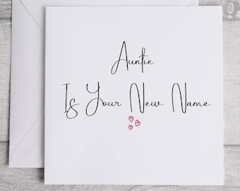 Puede incluir: Una tarjeta de felicitación cuadrada de color blanco con su sobre a juego. La tarjeta presenta el texto impreso en negro "Auntie Is Your New Name" en una fuente cursiva, acompañado de tres pequeños corazones rojos dibujados a mano.