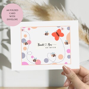 May include: A white card with a pink, orange and grey polka dot pattern. The card features a butterfly and bees flying around the dots. The text "Thank You So Much" is written in black cursive on the card.